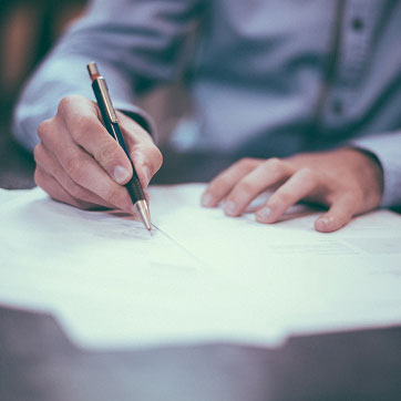 Billedet viser en mand som skriver under på sin ansættelseskontrakt.
