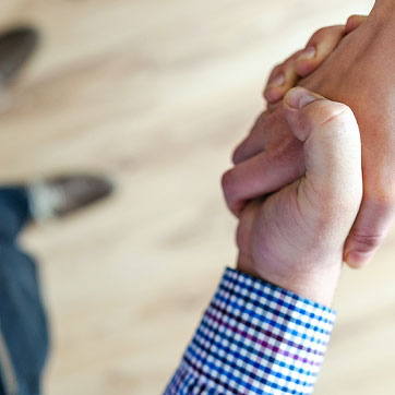 Billedet forestiller to mennesker som giver hånd til hinanden.